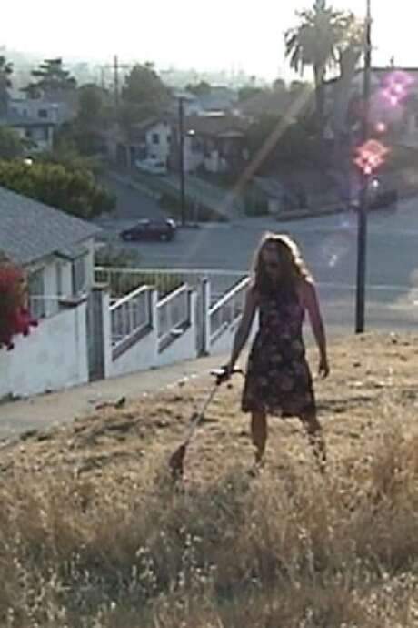    Under a cloudless Los Angeles sky, Kahn—dressed in incongruous heels and a summery dress—runs an electric weed whacker through a hill of overgrown grass.  